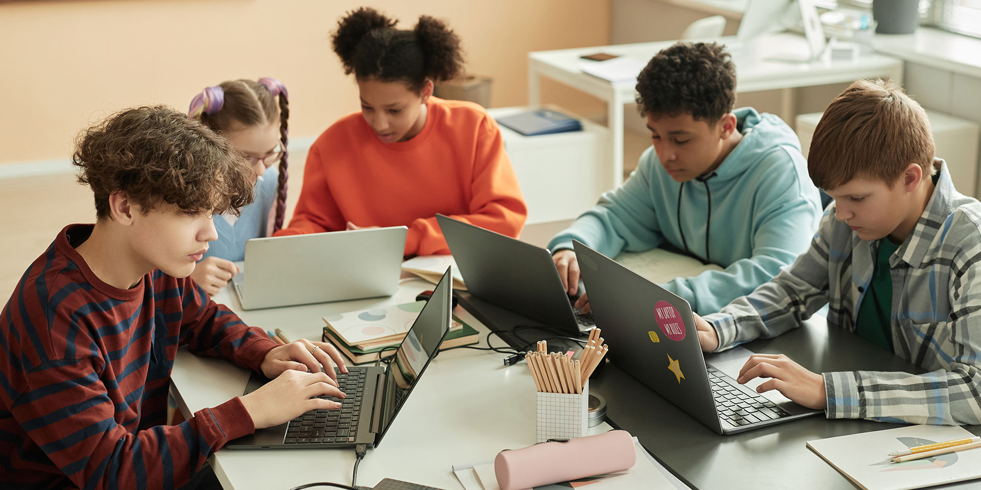 A group of students work on a project using laptops. 